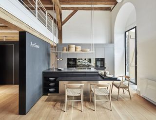 Interior of D Studio showroom showing a black kitchen island by Arclinea with light wooden chairs