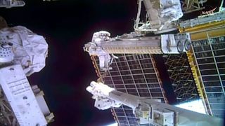 NASA astronaut Anil Menon carries a rolled-up solar array to the site where it will be deployed while riding on the end of the Canadarm robotic arm during a spacewalk outside the International Space Station on Thursday, Oct. 29, 2026. (Image