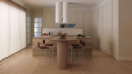 An airy, minimalist open plan kitchen and dining room with a wood table, a stone island, maroon chairs with gray frames, and storage all around