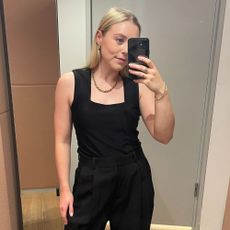 Woman wears black tank top and black tailored trousers
