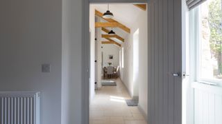 narrow hallway with exposed beams and limestone flooring
