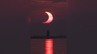 A partial solar eclipse is seen as the sun rises behind the Delaware Breakwater Lighthouse, Thursday, June 10, 2021, at Lewes Beach in Delaware.