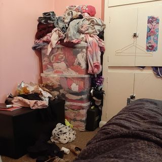 messy bedroom with plastic storage boxes and pink walls