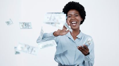 A woman smiles with joy as she tosses money into the air.