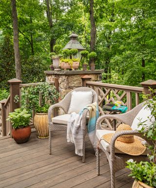 spring backyard patio decorated with potted plants and two wicker chairs