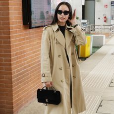 Sofia wears a trench coat, chanel bag, black trousers, and adidas samba sneakers.