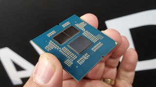 A delidded AMD Ryzen 9000 series processor held in a hand, showing the two CCD and one IOD chiplets