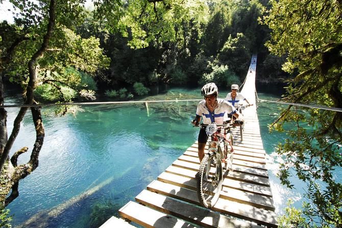 Two riders cross a bridge during stage 1