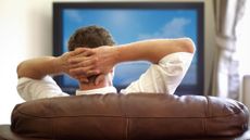 A relaxed man watching TV on a couch