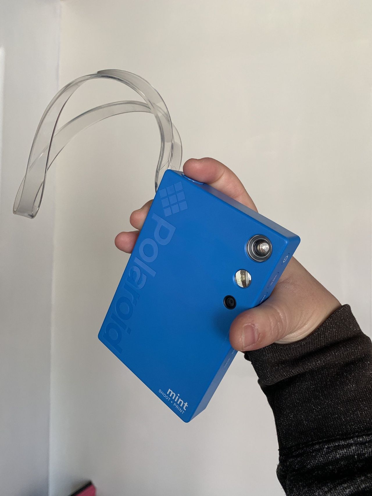 Blue Polaroid Mint Camera &amp; Printer held in hand to demonstrate where the shutter button is