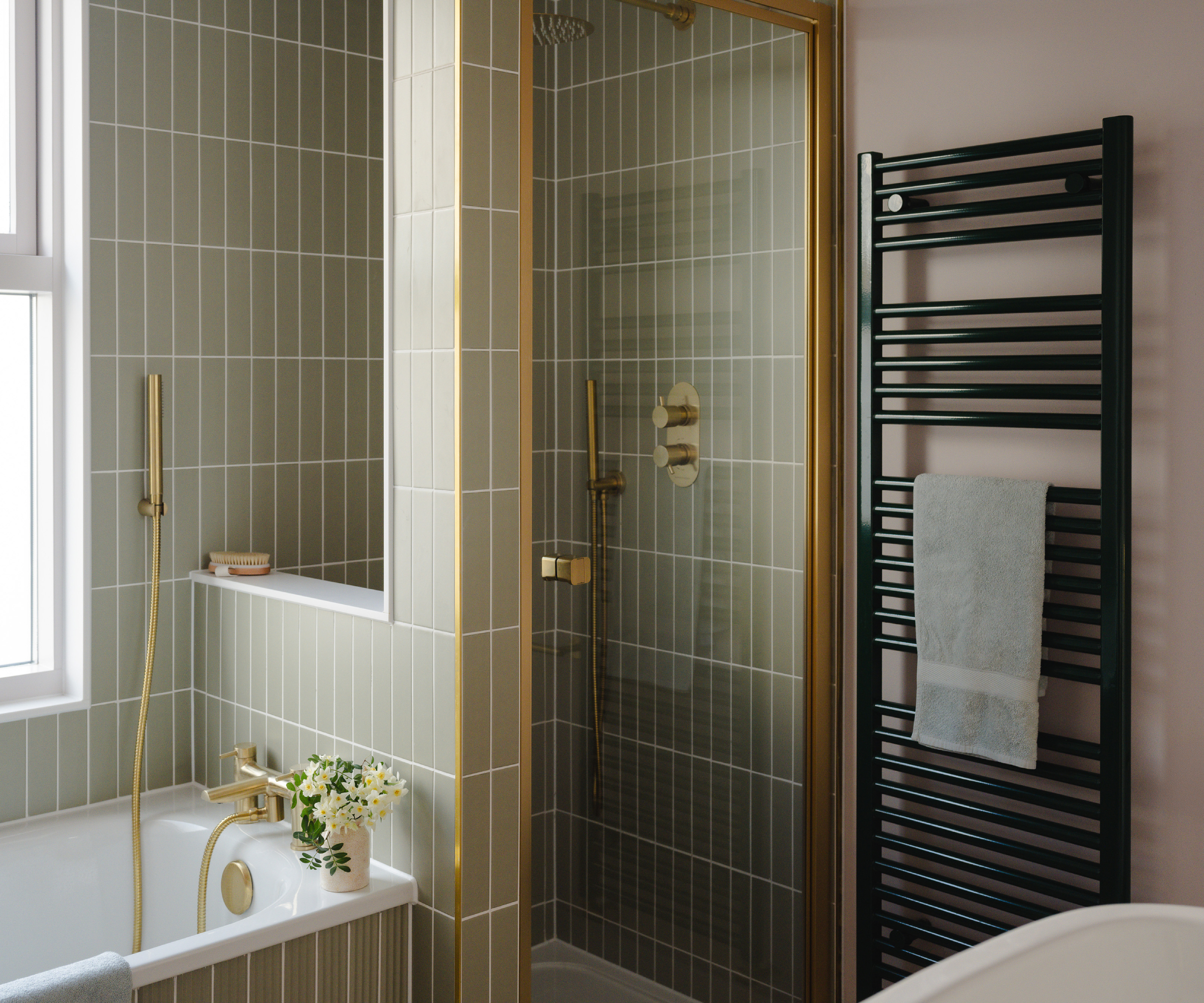 black towel radiator on wall next to shower cubicle and built in bath