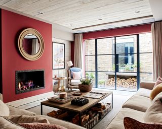 Fireplace in living room with red wall decor, mirror and cream furniture