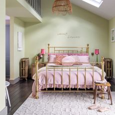 green bedroom with brass bed and pink bedlinen