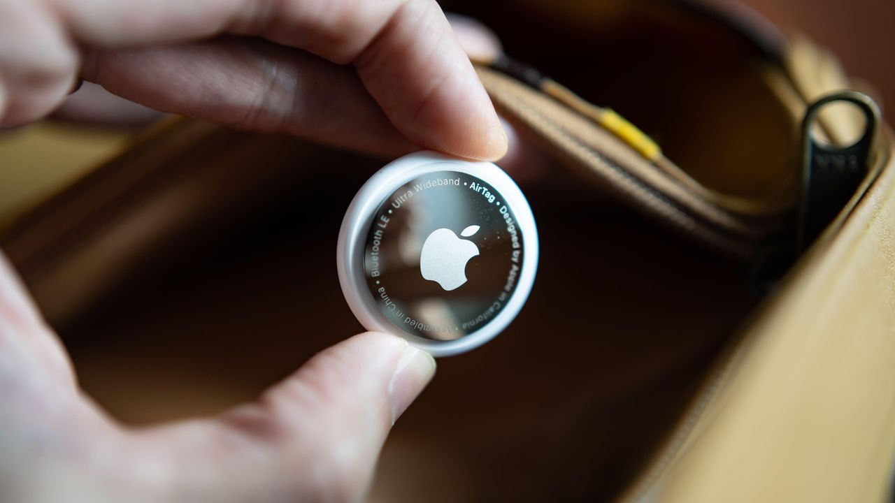 Apple Airtag being held between two fingers by person