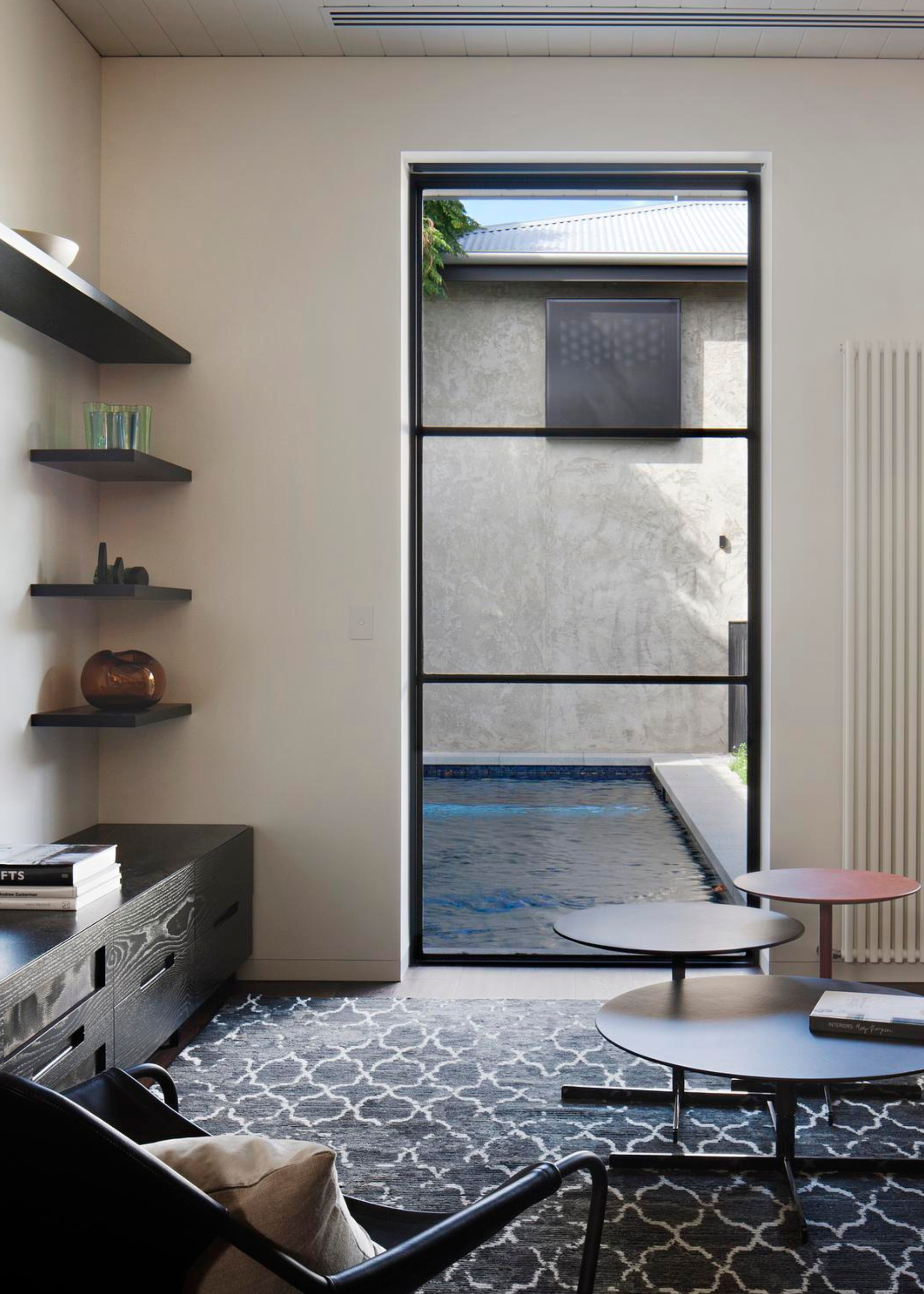 a living room with a large window that looks out directly to a swimming pool