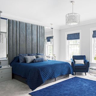 bedroom with a grey oversized headboard and blue bedspread