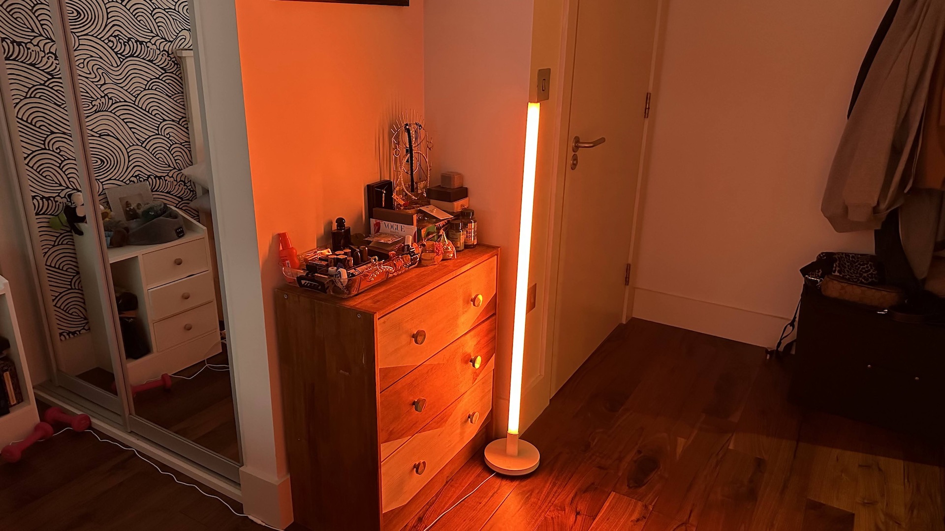 Wiz Luminaire Pole Floor Light glowing orange in a living room corner.