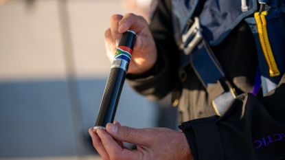 We see a man holding a black tube.