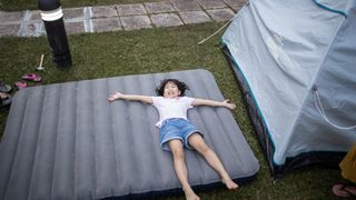 Little girl on an air mattress next to a tent