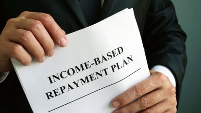 Man in a suit holding a piece of paper in his hands that reads "Income-based repayment plan"