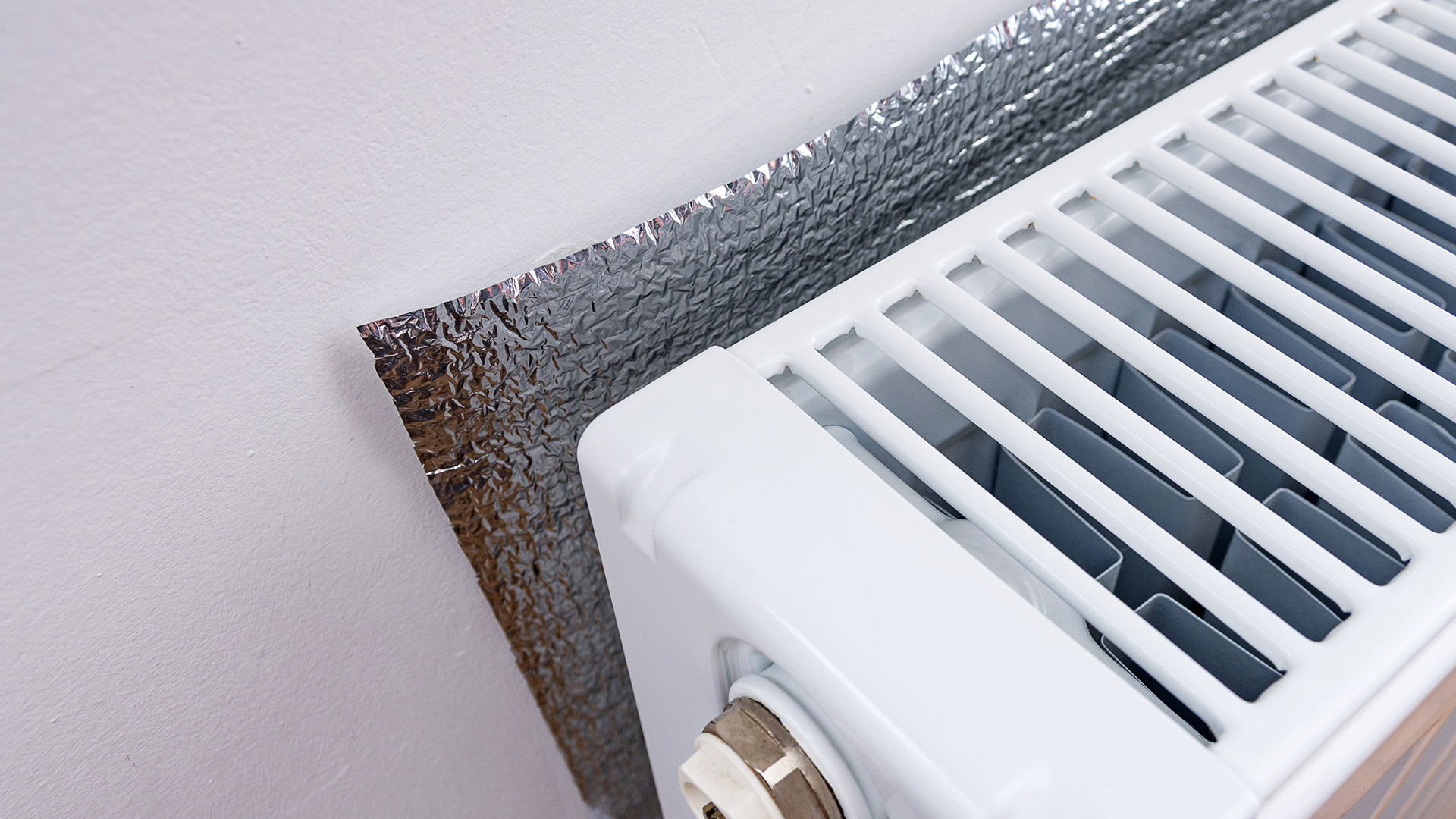 close up of the top of a white radiator with foil behind it