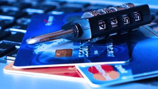 A pile of credit cards being weighed down by a heavy padlock.