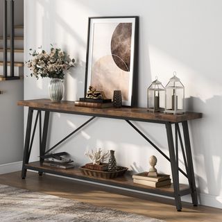 Wood and black metal entryway console styled with lanterns, books and flowers on top, woven basket underneath