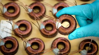 Worker holding electromagnetic coils in electromagnetics factory, close-up. Monty Rakusen via Getty Images