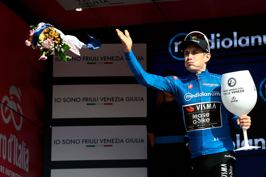 Jonas Vingegaard tosses a bouquet of flowers from the mountains classification podium