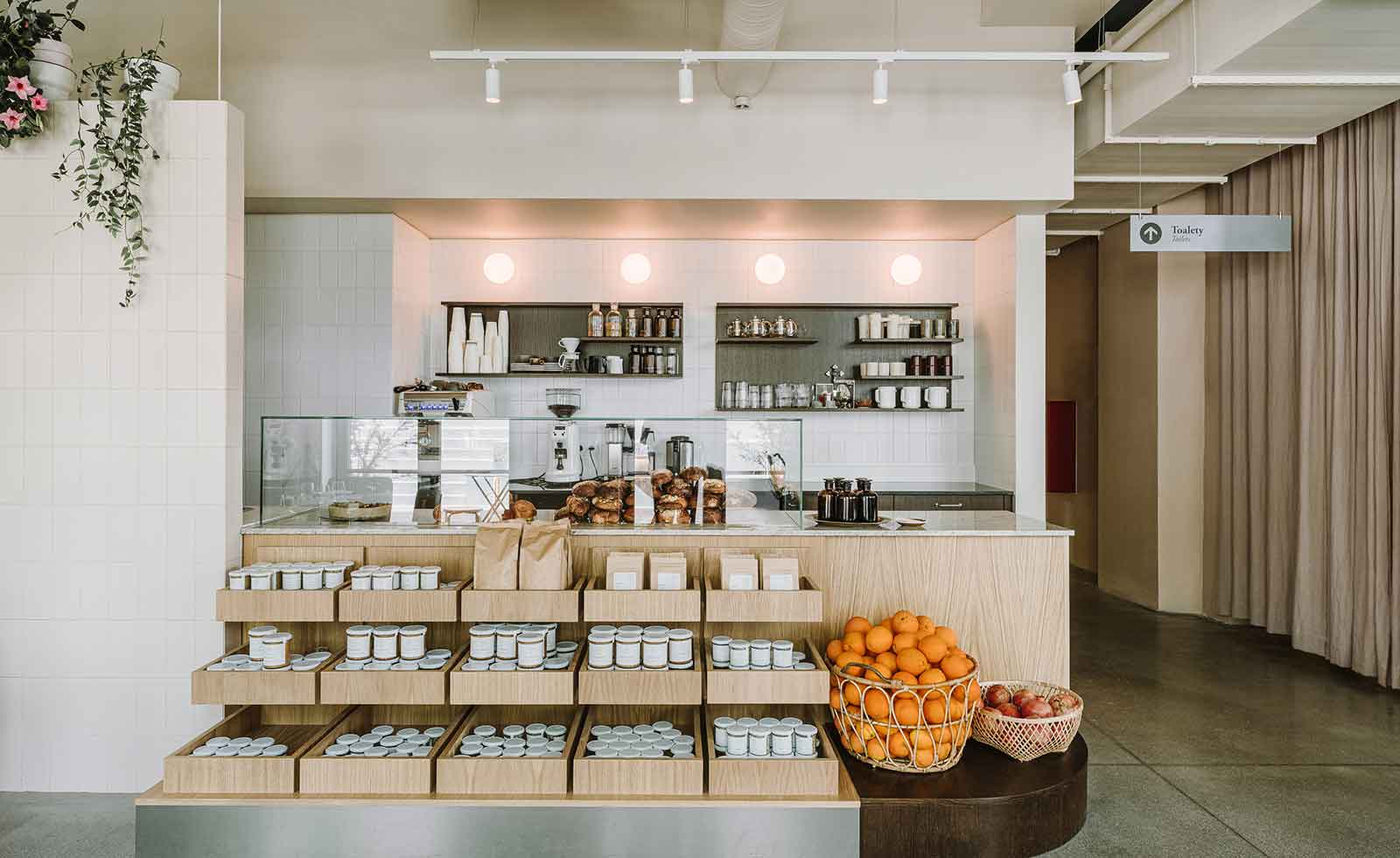 Counter with a glass cabinet of baked good, shelves of preserves and baskets of fruit