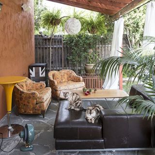 shaded terrace area with red wall and black sofa