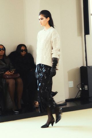 Altuzarra fall 2024 model wearing black leather gloves, black sequin skirt, white sweater