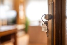 House-shaped keys are hanging from the door knob of a new home