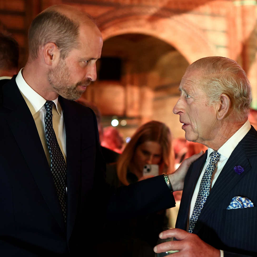Prince William wears a suit and looks at his father King Charles