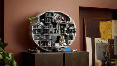 A look at the interior of a fictitious space station in toy brick form, with many different rooms and characters, placed on a wooden surface.
