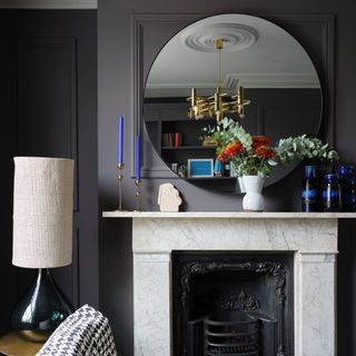 Victorian fireplace with marbled mantelpiece, grey panelled walls and large circular mirror