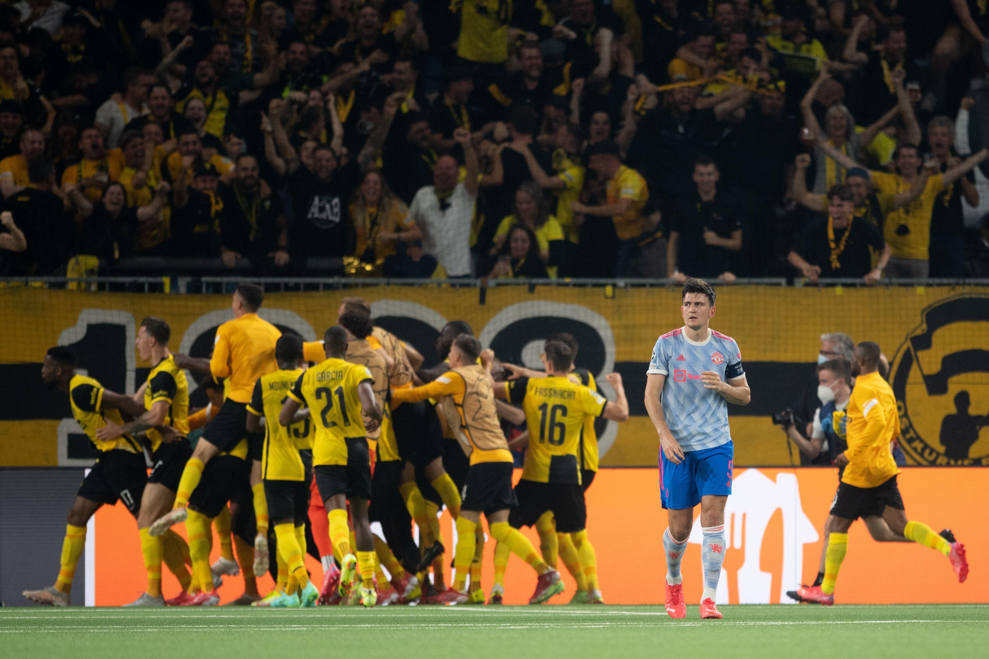 Young Boys celebrate their late winning goal against Manchester United in the 2021/22 Champions League group stage, as Harry Maguire walks away dejected