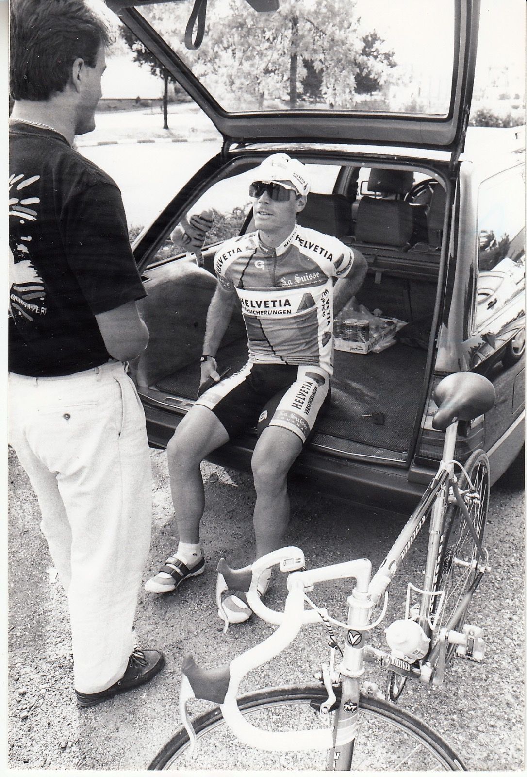 Yves Perret speaks to Steve Bauer from the back of his car