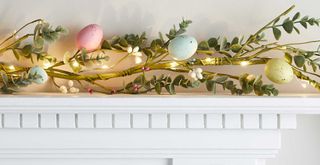Easter garland with pastel eggs and lights entwined along twigs as a simple Easter mantel decor idea