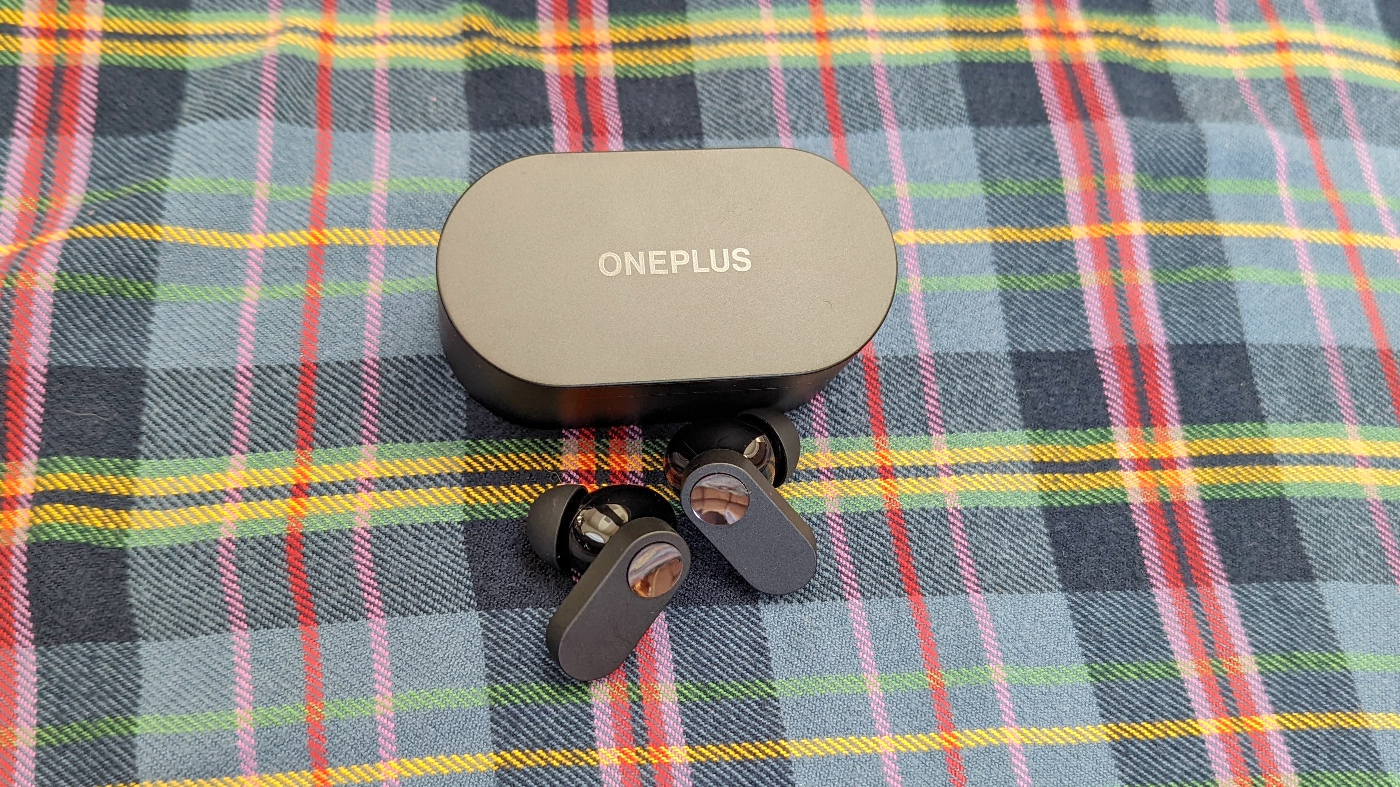 The OnePlus Nord Buds resting on plaid fabric