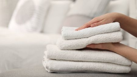Hands stacking freshly washed, soft white bath towels