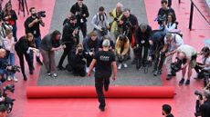 An employee rolls out the red carpet outside the Palais des Festivals in Cannes, while photographers take pictures