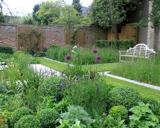 walled garden design with mix of evergreens and perennial planting and Lutyens bench