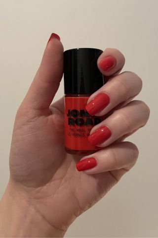 valeza with red nails holding the poppy polish