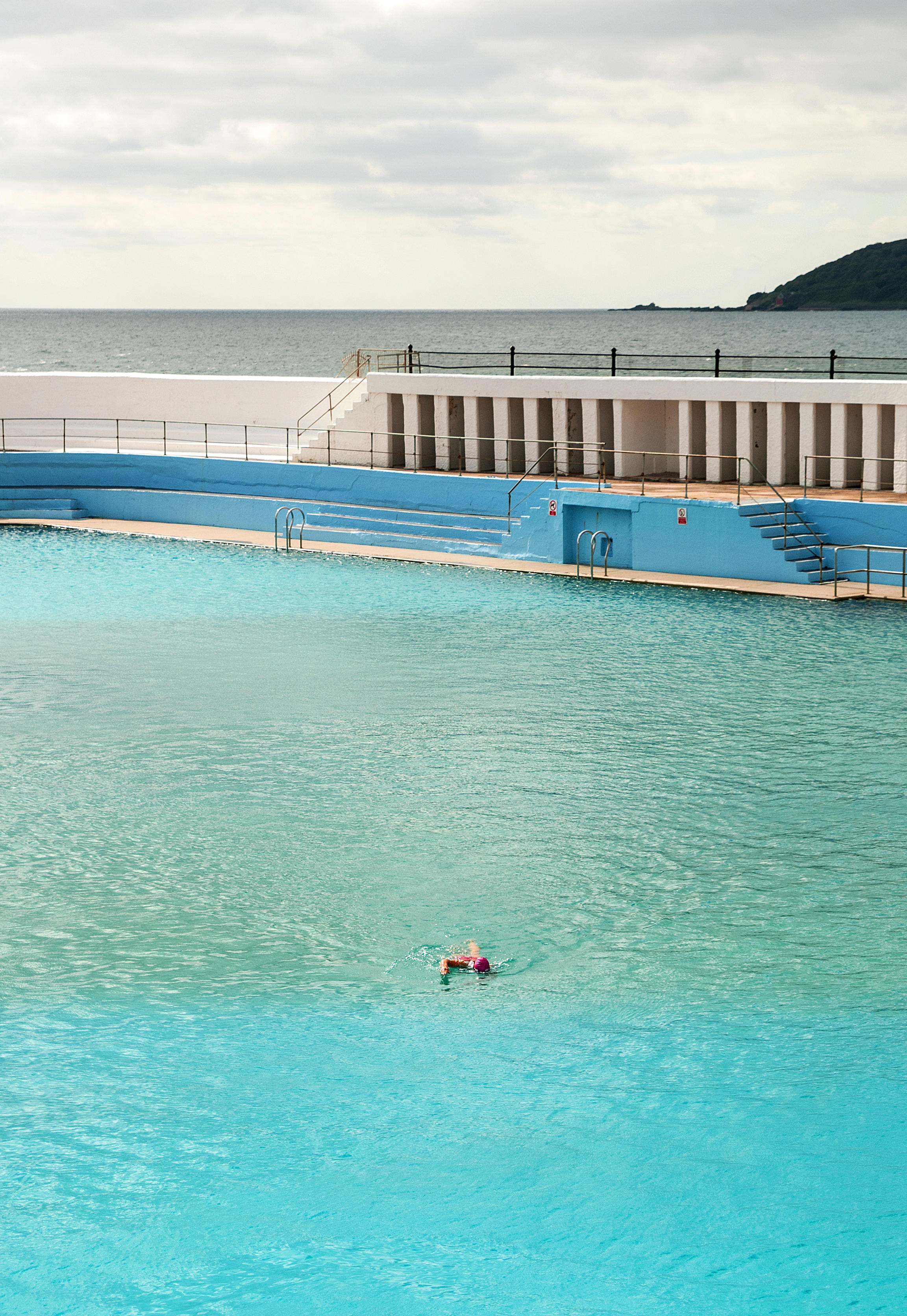 Lone swimmer in a lido overlooking the sea