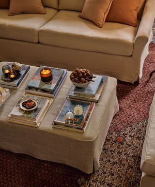 A coffee table with stacked books, candles, and bowls