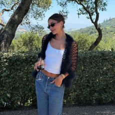 Hailey Bieber wearing sunglasses and holding wine