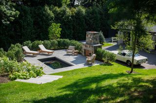 A plunge pool in a yard with loungers and a classic car parked alongside