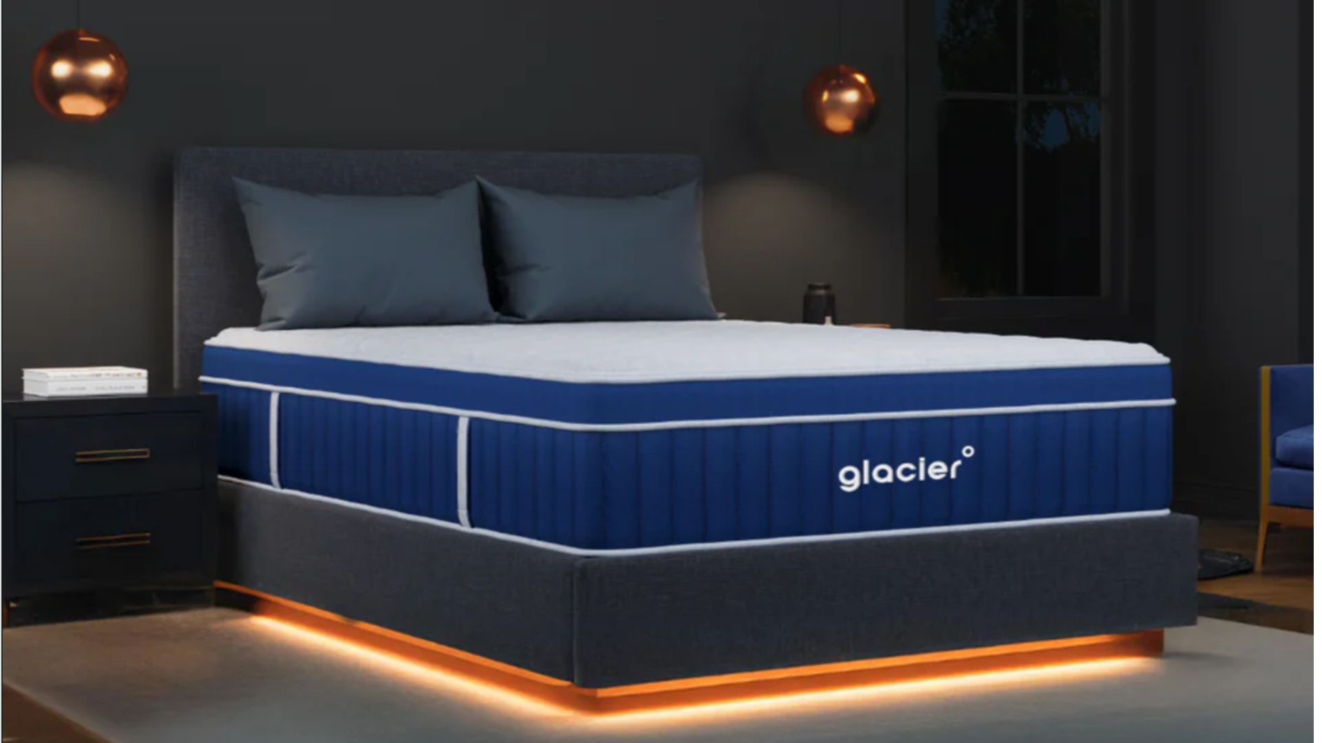 Marineblaue und weiße Glacier-Matratze auf einem Bettgestell mit Kupferlichtern in einem dunkelgrauen, eleganten Schlafzimmer.