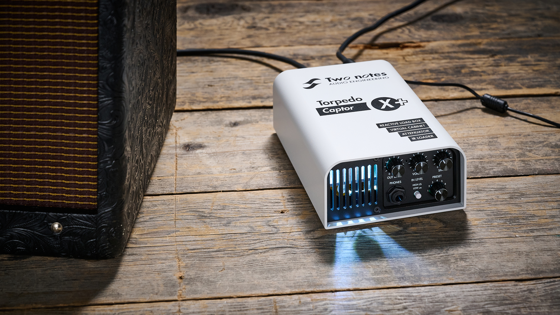 A Two Notes Torpedo Captor X Plus load box on a wooden floor next to a Fender tube amp